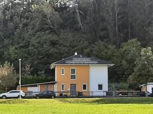 罗伊特Ferienhaus mit 4 Zimmer am Lech的一座黄色和白色的房子,汽车停在田野里