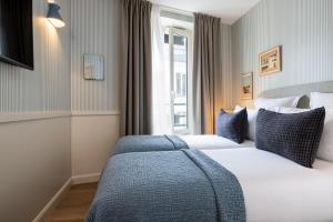 巴黎Le Petit Oberkampf Hotel & Spa的酒店客房设有两张床和窗户。