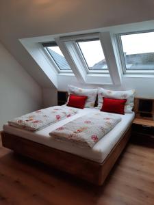 萨尔茨堡Apartments Brunnmeisterhof的窗户间内的一张带两个红色枕头的床