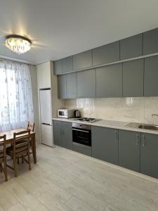 敖德萨Sky apartments Budova的厨房配有灰色橱柜、桌子和桌椅