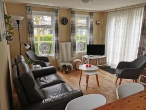 BaarlandChalet - Dà gae nog à的客厅配有黑色真皮沙发和椅子