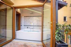 博洛尼亚Falegnami Boutique Suites - BolognaRooms的带浴缸和玻璃墙的浴室