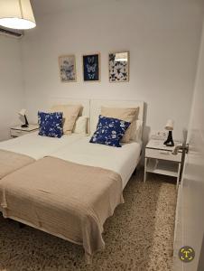 塞维利亚Plaza de Armas的一间卧室配有两张带蓝白色枕头的床