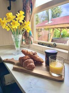 约克Alice’s Garden @ Bleak House Farm的一张桌子,上面有面包和一杯橙汁及鲜花