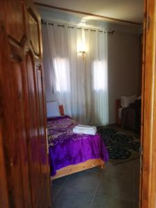阿伊特本哈杜Riad Ouinz的一间卧室配有一张带紫色床单的床和窗户。