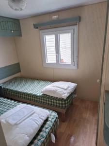 佩内斯坦Mobil-home dans camping calme的带窗户的客房内的两张床