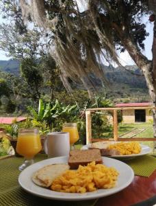 MachetáHotel Campestre Rocas Del Paraíso的一张桌子,上面放着两盘食物和橙汁