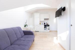 卢加诺San Carlo Apartments的一间带紫色沙发的客厅和一间厨房
