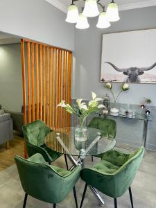 彼得马里茨堡Mdumela Stays 2 Bedroom Modern City Apartment的一间设有玻璃桌和绿色椅子的用餐室