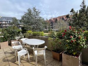 多维尔Côté Jardin - Terrasse, Calme et Cosy的鲜花庭院里的白色桌子和椅子
