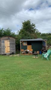 奥斯威斯Willowdene shepherds hut的一个带棚子和桌椅的庭院