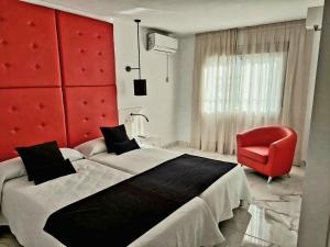 多列毛利诺斯Villa Musica的一间卧室配有一张大床和一张红色椅子