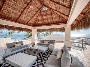 布塞里亚斯Villa Cobojo的带沙发的室外客厅和茅草屋顶。