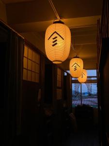 MurayamaYamagata Guesthouse山形ゲストハウス的天花板上挂着三盏灯笼,关在一间黑暗的房间里