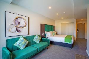 惠灵顿The Sebel Wellington Thorndon的酒店客房,设有一张床铺和一张绿色沙发