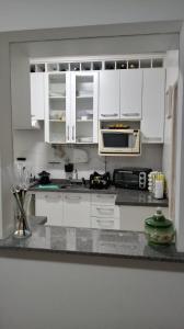 伊塔尼亚恩Mar, Praia, Sossego e Tranquilidade的白色的厨房配有白色的橱柜和微波炉