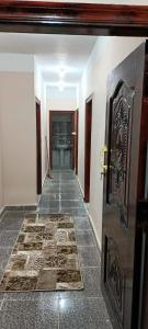 ‘Izbat ŢanāţīDakrour flat的走廊上设有门,铺有瓷砖地板