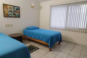 巴拉德纳维达Casa Las Palmas Barra de Navidad, Jalisco.的一间卧室设有两张单人床和一个窗户。