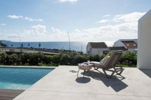 蓬塔德尔加达Green&Houses的坐在游泳池旁的椅子,享有海景