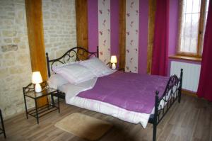 Laferté-sur-Aube金矿度假屋的一间卧室配有一张带紫色床单的床和两盏灯。