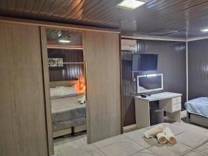 卡内拉Chalé D´Roos III的一间卧室配有一张床、一张书桌和一台电视