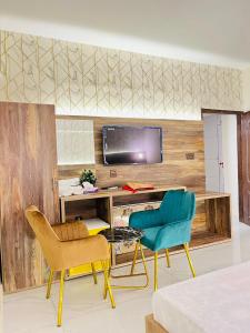 卡拉奇TULIP HOTELS AND APPARTMENTS的客房设有2把椅子和1张带电视的书桌。