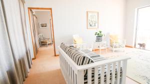 阿尔弗雷德港A-View-at-Kingfisher Port Alfred Guest Accommodation的白色的房间里,一张白色的婴儿床,配有一张桌子