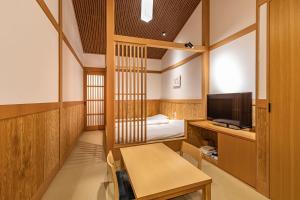 箱根仙石原芒草原一之汤日式旅馆的客房设有床、书桌和电视。