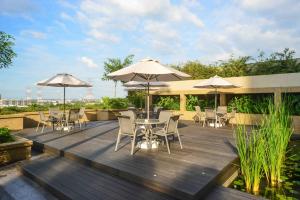 北赖槟城日光酒店的木甲板配有桌椅和遮阳伞