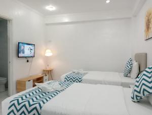 长滩岛碧海蓝天沙滩酒店的白色客房内的两张床,配有蓝色和白色枕头