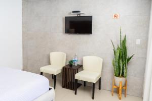 圣安娜Equinoccio Hotel的两把椅子和一张桌子,墙上配有电视