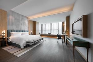 青岛青岛东方影都创智君亭酒店的酒店客房配有一张床、一张书桌和一张书桌。