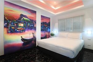 芭东海滩PATONG TOWER SEA VIEW for FAMILY's by PATONG TOWER AGENCY的卧室配有一张床,墙上挂有绘画作品