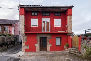 卡马乔Precioso piso estilo rústico a 10 min de Santander的街道上带阳台的红色房子