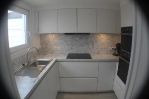 德哈恩"Zee en rust"的厨房配有白色橱柜、水槽和窗户。