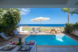 普罗塔拉斯Jasmine Sea Front Villa的一个带椅子和遮阳伞的游泳池以及大海