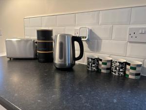 LincolnshireNumber 3 Seafield - sleeps 4 - Grantham town的咖啡壶,坐在厨房的柜台上,配有咖啡杯
