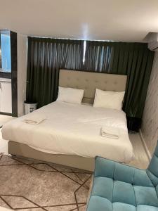 耶路撒冷Lago Suites Hotel的卧室配有一张白色大床和一张蓝色椅子