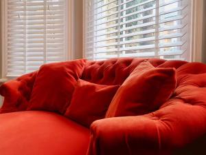 特威克纳姆Stylish Studio Apartment, ensuite, kitchenette的窗前的红色沙发