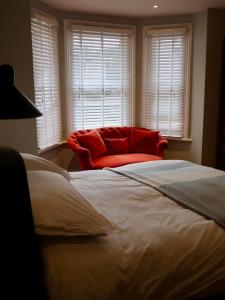 特威克纳姆Stylish Studio Apartment, ensuite, kitchenette的一间卧室配有一张大床和一张红色椅子