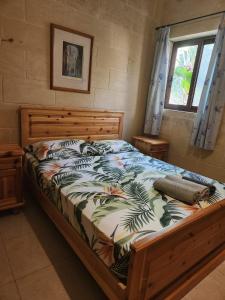 Għajn il-KbiraExclusive Pool with your own views with 3 bedrooms and 4 bathrooms in Gozo的一间卧室配有一张木框床和窗户。