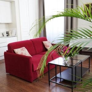第比利斯TIFLIS OPERA Aparthotel的客厅里一张红色的沙发,配有桌子