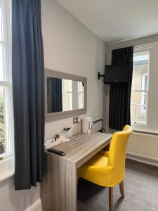 德罗伊特威奇圣安德鲁斯小镇酒店的一张带黄色椅子和镜子的桌子