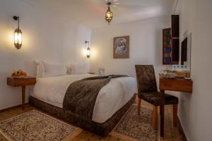 马拉喀什riad dar nejma & Spa的一间卧室配有一张床、一张桌子和一把椅子