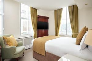 伦敦The Prime London Hotel的配有一张床和一把椅子的酒店客房