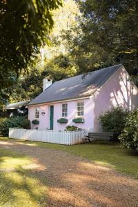 谭伯连山Enchanting Retreat - The English Cottage at Tamborine Mountain的前面有长凳的白色房子