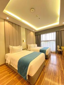 TanauanBravo Tanauan Hotel的酒店客房设有两张床和一张桌子。