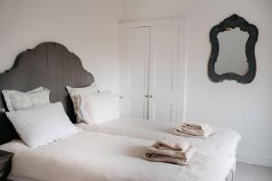 里士满3 Bedroom House in Kew Gardens的白色卧室配有两张带毛巾的床