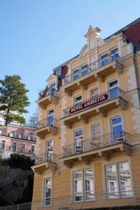 卡罗维发利Hotel Villa Lauretta的一座高大的黄色建筑,上面有标志