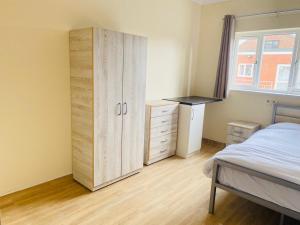 MoultonEn-suites Rooms in Northampton的一间卧室配有一张床、梳妆台和衣柜。